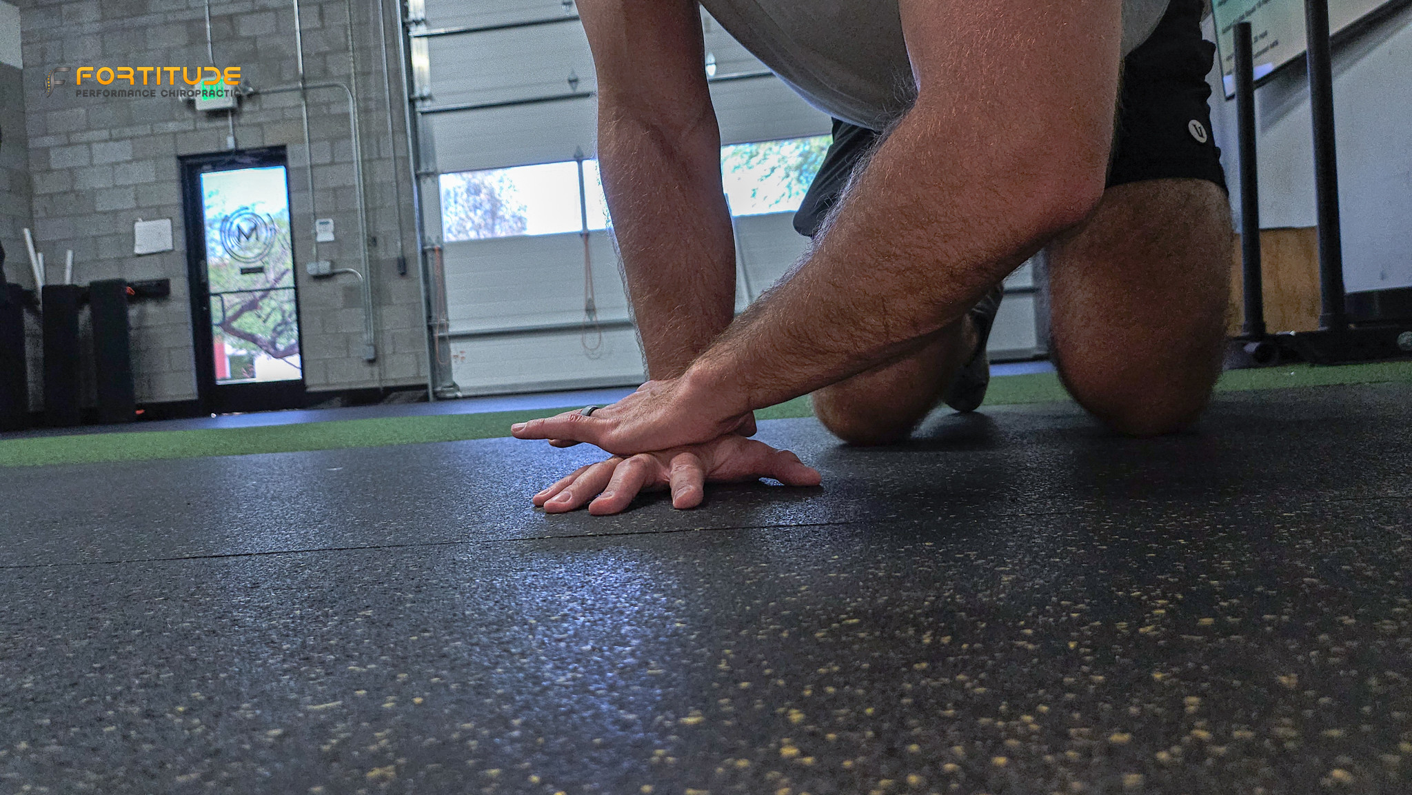 forearm stretch on gym floor with fingers extended backward, targeting wrist mobility and flexor tension relief