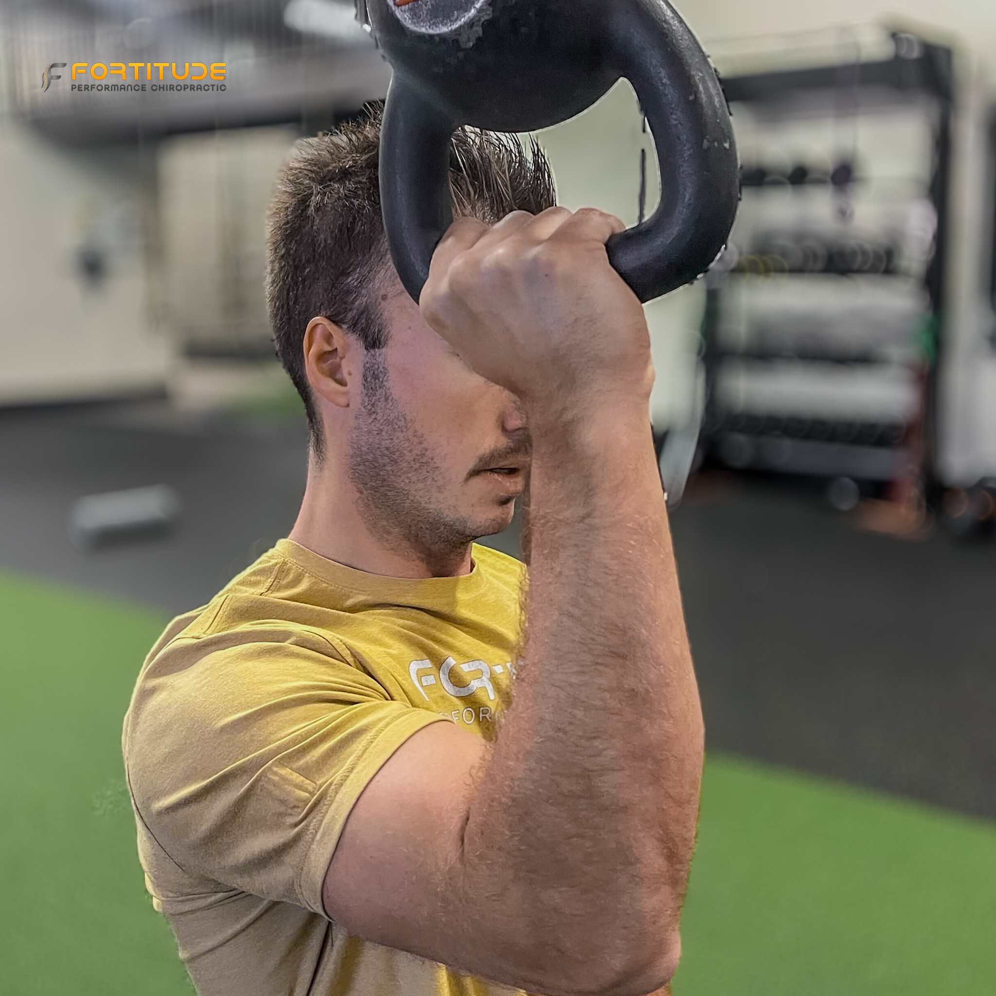 man performing kettlebell press to improve elbow stability and upper body control during sports rehab at Fortitude Performance Chiropractic