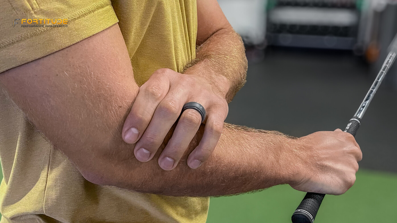 Golfer gripping elbow in pain during swing, demonstrating symptoms of golfer’s elbow or forearm strai
