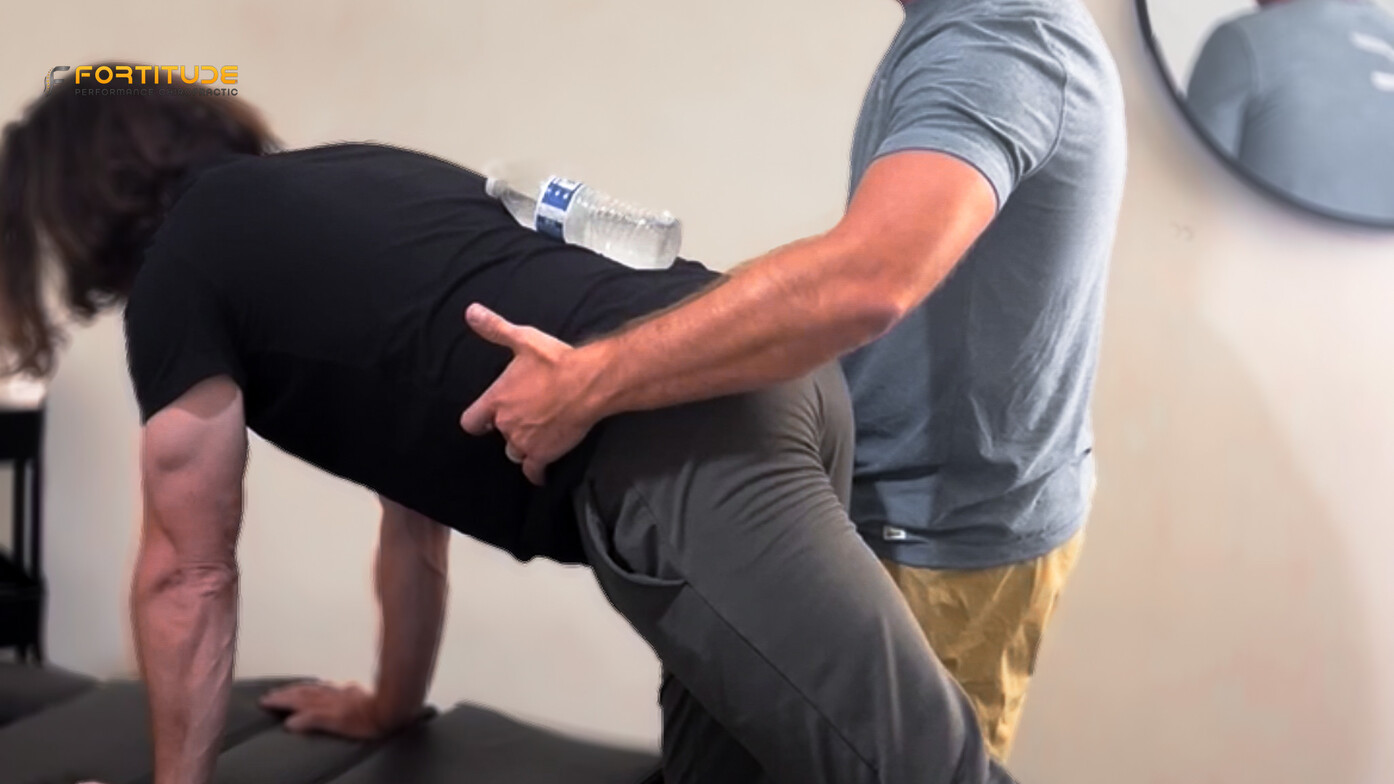 Chiropractor coaching a patient through a side plank to improve core strength and reduce golf-related back pain.
