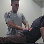 Chiropractor guiding patient through prone press-up exercise to relieve lower back tension and sciatic nerve pressure.