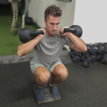 Male athlete performing a front-loaded squat on slant boards