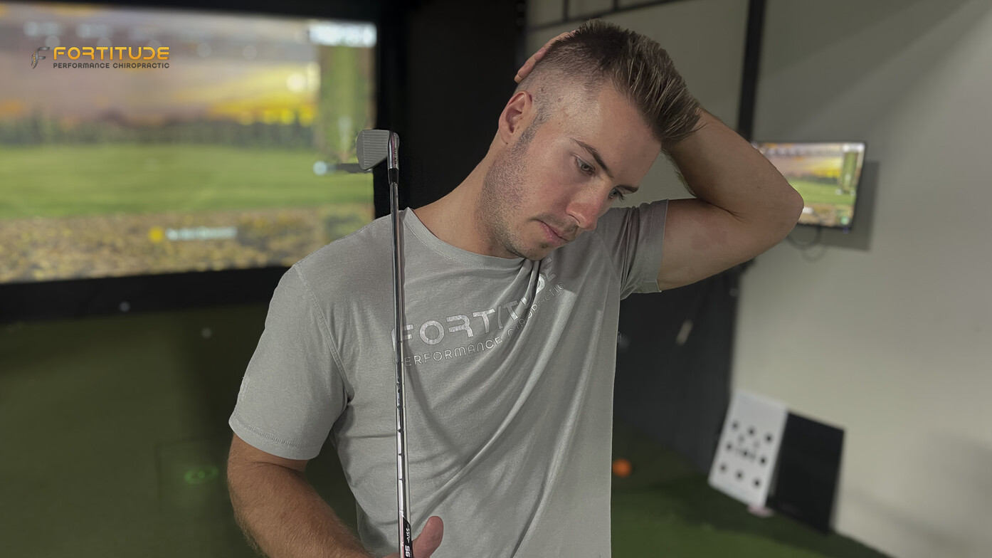 Golfer Gently Stretching Neck  to relieve neck pain in front of Golf Simulator