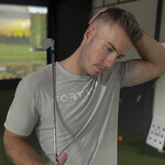 Golfer Gently Stretching Neck  to relieve neck pain in front of Golf Simulator