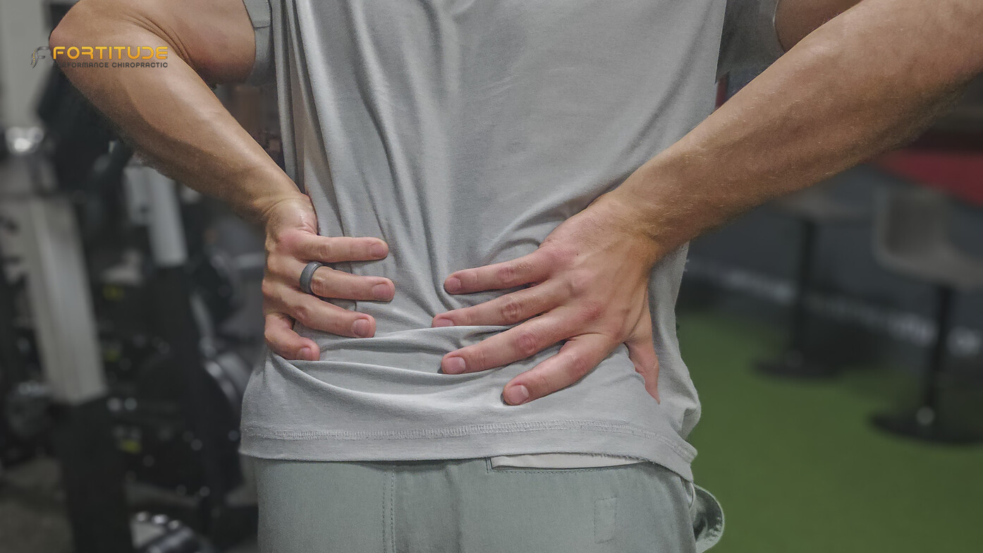 person holding back in pain with both hands at a chiropractor clinic demonstrating cortisone shot ineffectiveness